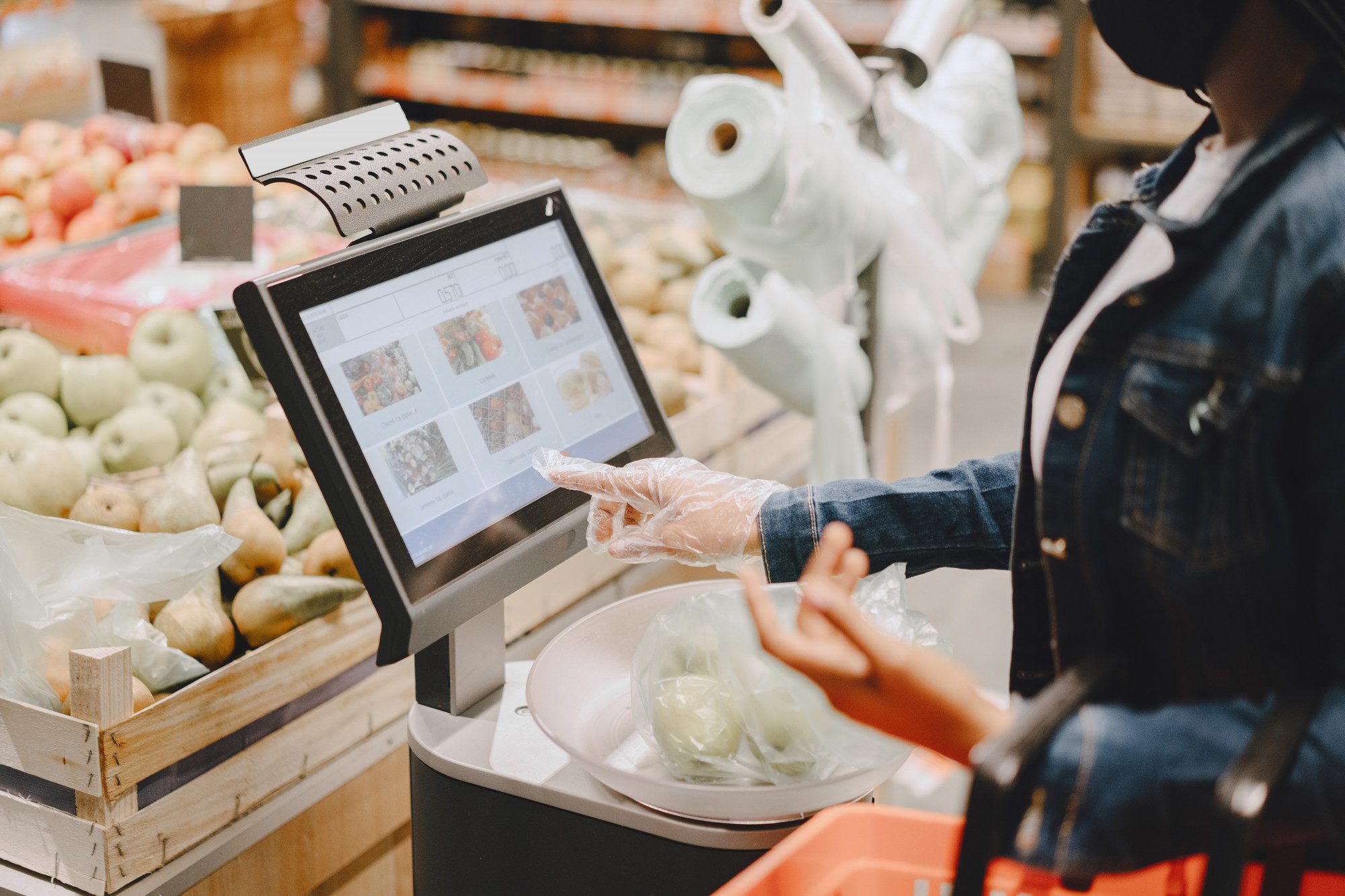 Person shopping groceries using a touchscreen kiosk in a store.
