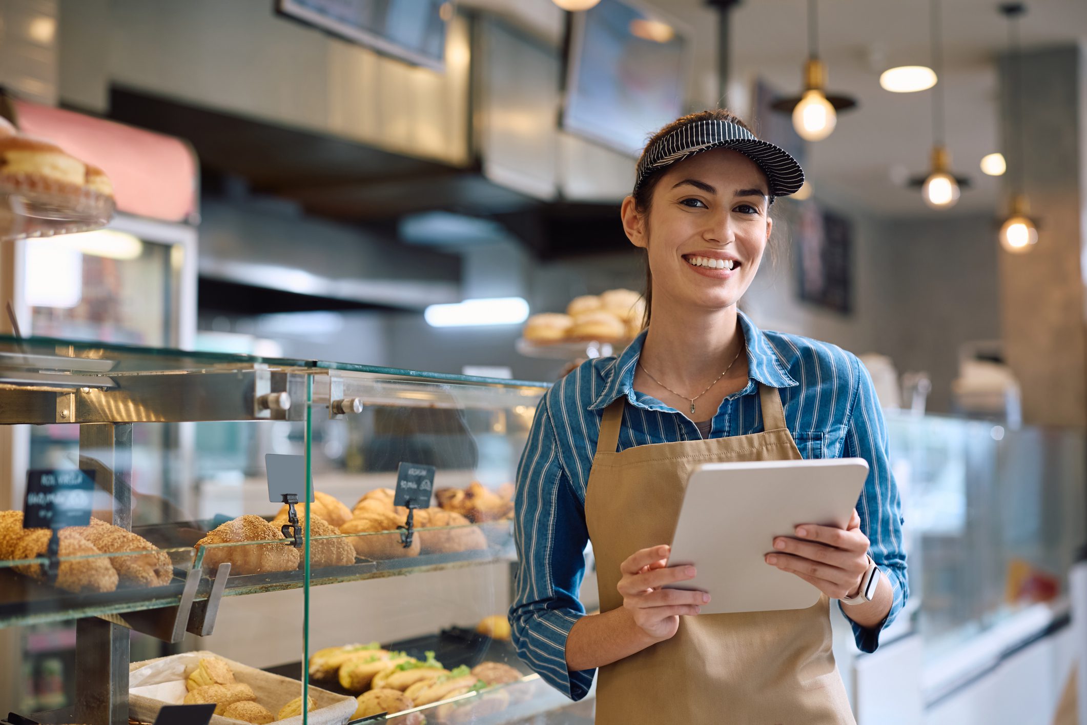 Bakery worker smiling with tablet in hand.